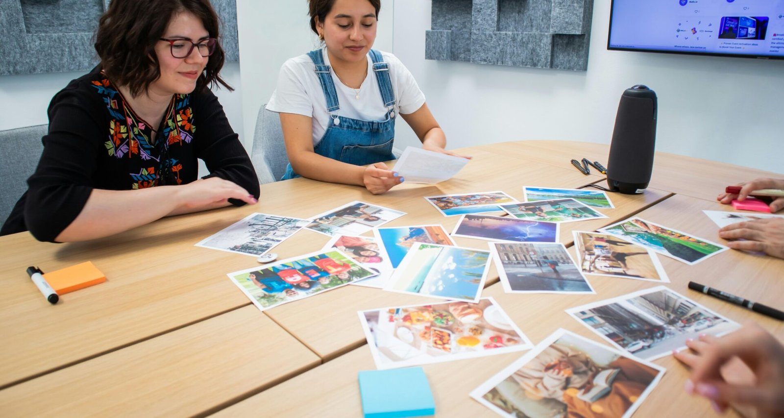 Mehrere Personen sitzen um einen rechteckigen Holztisch und arbeiten gemeinsam an Laptops und Notizbüchern.