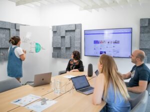 Mehrere Personen sitzen mit Laptops an einem Tisch und diskutieren gemeinsam über digitale Projekte