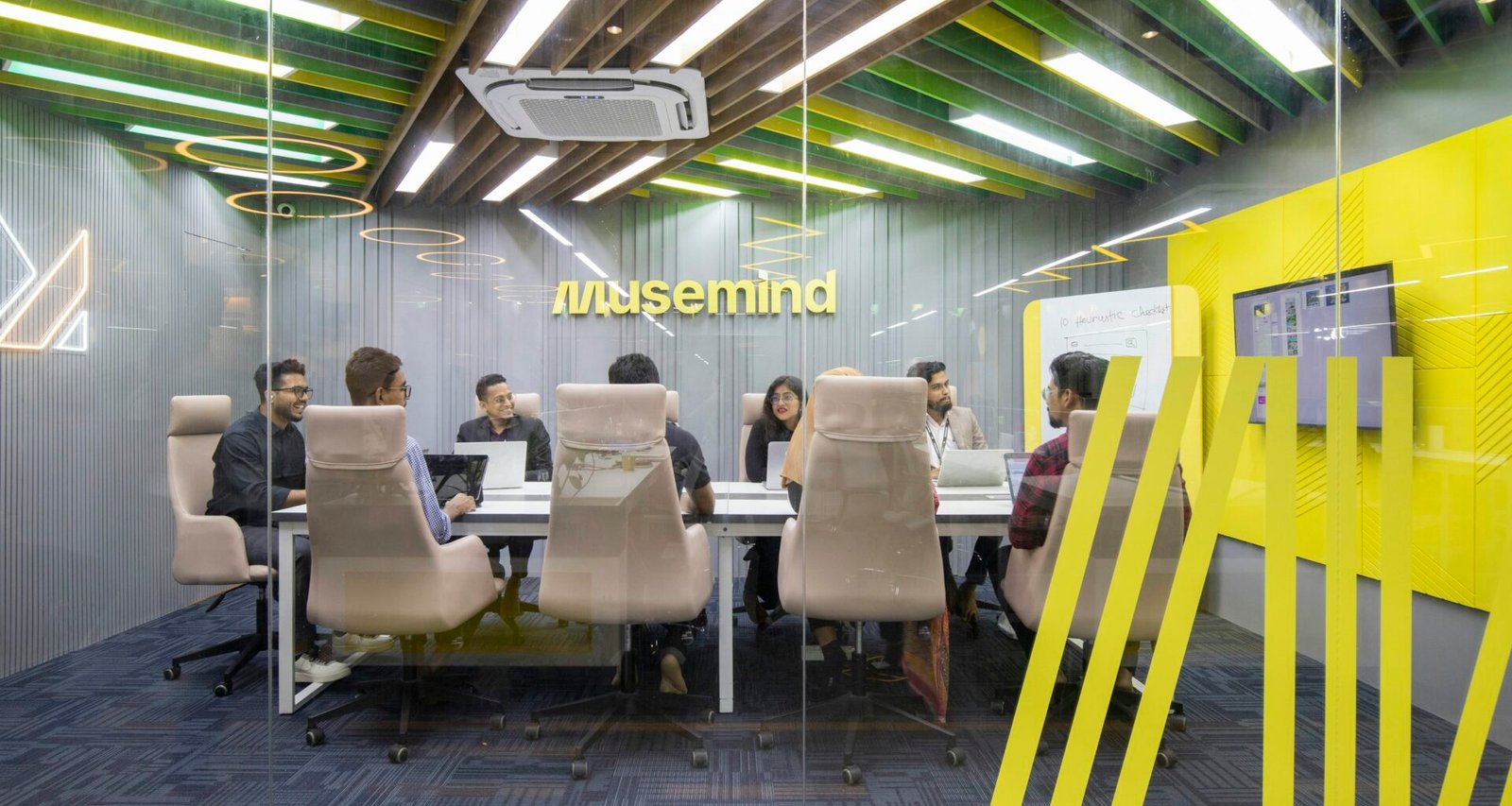Mehrere Personen sitzen um einen Konferenztisch und arbeiten gemeinsam an einem Projekt im Büro.