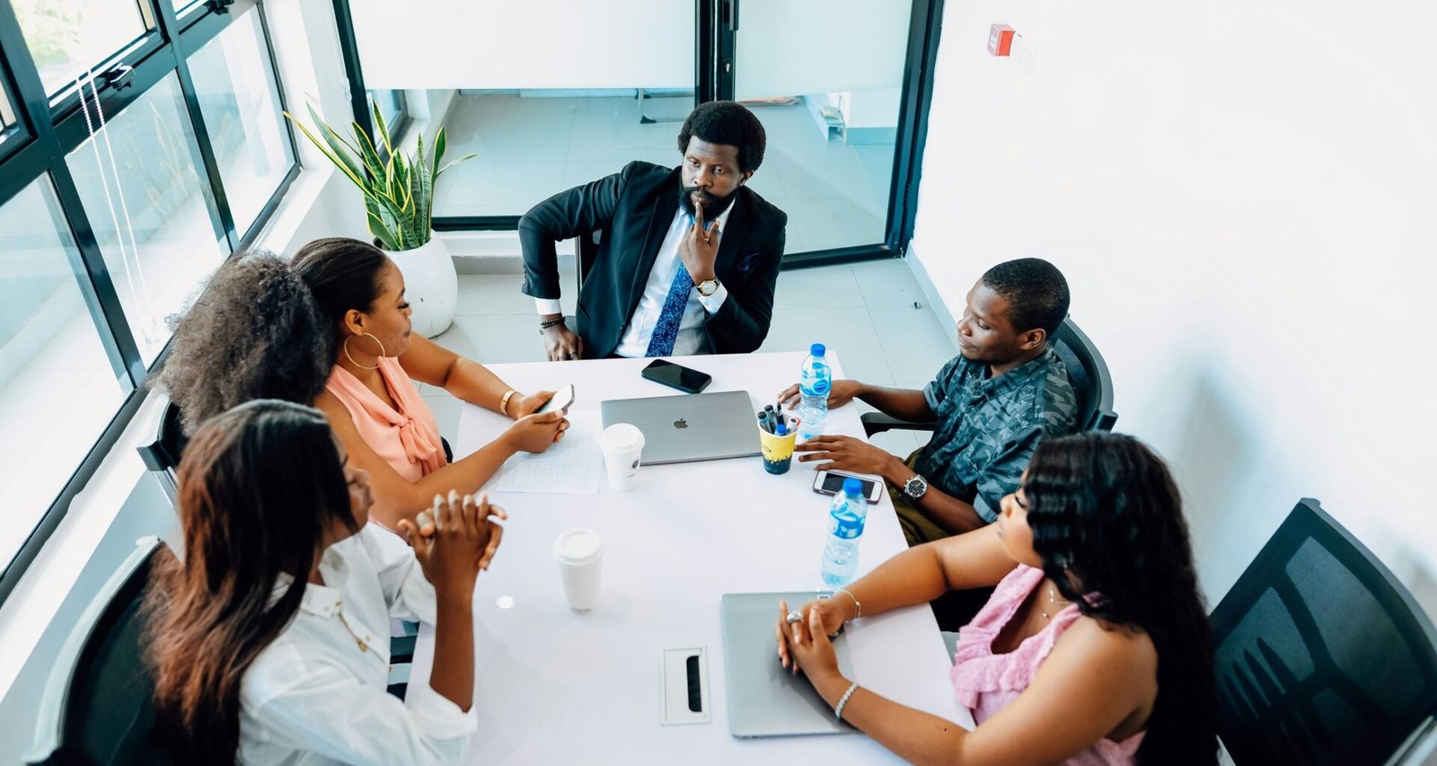 Mehrere Personen sitzen um einen weißen Tisch und diskutieren Ideen während eines Meetings im Büro.