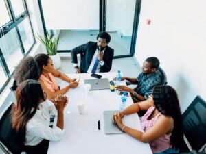Mehrere Personen sitzen um einen weißen Tisch und diskutieren Ideen während eines Meetings im Büro.