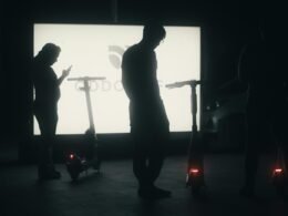 Mehrere Personen versammeln sich vor einem großen Bildschirm und beobachten gemeinsam eine Präsentation in einem modernen Büro.