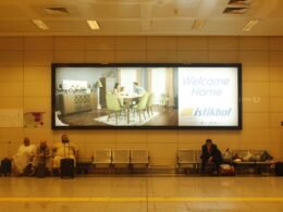 Mehrere Personen sitzen gemeinsam auf einer Bank vor einem großen Bildschirm und verfolgen eine Präsentation