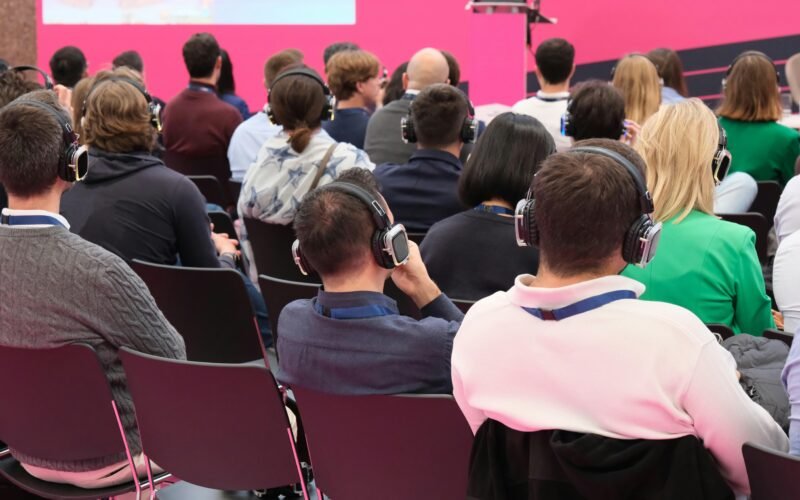 Mehrere Personen sitzen gemeinsam vor einer pink gefärbten Wand, Symbol für Teamarbeit in urbaner Umgebung.