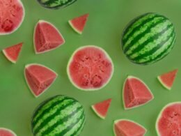 Mehrere Wassermelonen mit grüner, gesprenkelter Schale liegen eng beieinander und bilden eine natürliche Gruppe.