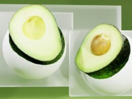 Eine reife Avocado wurde der Länge nach halbiert und auf einem weißen Teller platziert, Kern sichtbar.