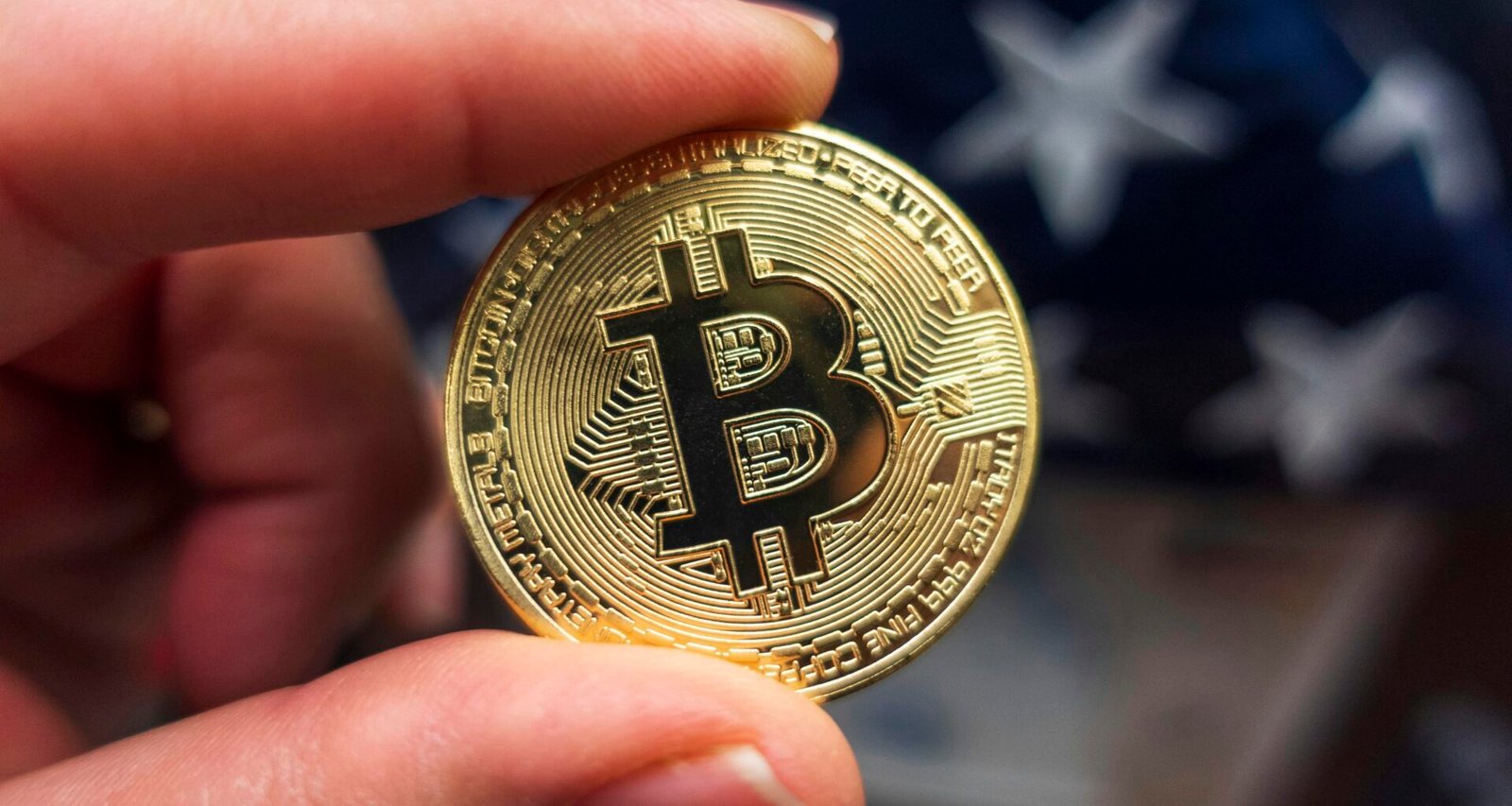 Hand hält eine Bitcoin-Münze vor einer amerikanischen Flagge, Symbol für Kryptowährungen und ihren Einfluss in den USA