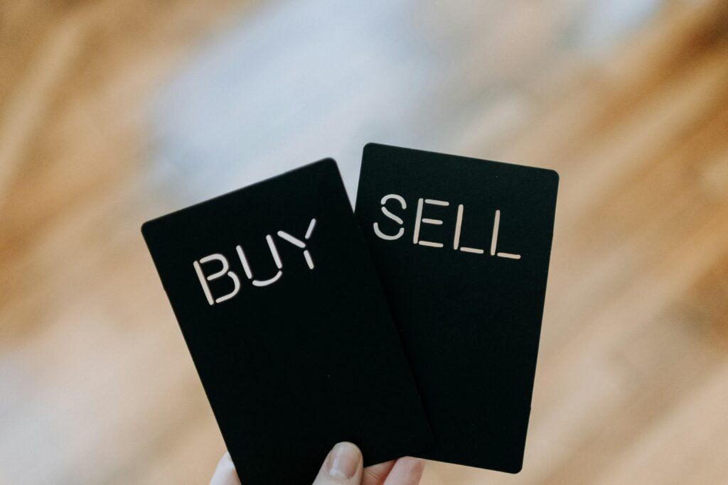 Hand hält zwei schwarze Karten mit der Aufschrift Buy und Sell – Symbolbild für Handelsentscheidungen im Online-Bereich