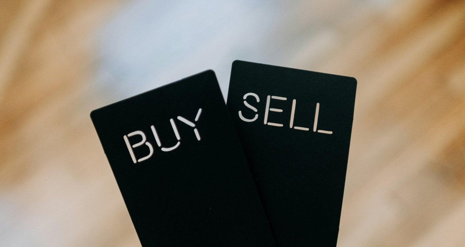 Eine Hand hält zwei schwarze Karten mit den Worten Buy und Sell, sinnbildlich für Online-Marketing-Prozesse.
