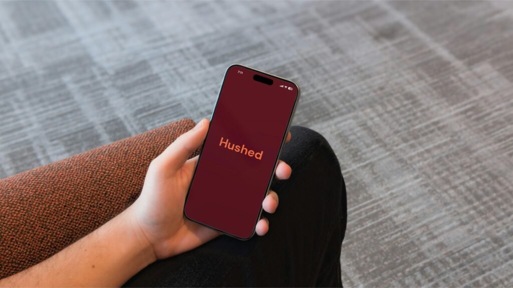 Hand mit Smartphone zeigt die Hushed-App auf dem Display, Fokus auf mobile Kommunikation und Datenschutz mit moderner Technologie.