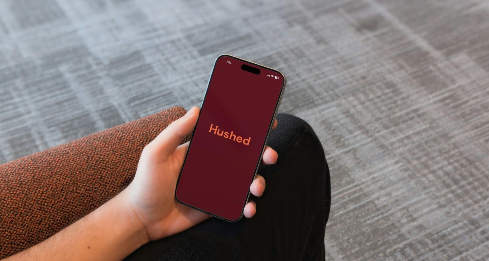 Hand mit Smartphone zeigt die Hushed-App auf dem Display, Fokus auf mobile Kommunikation und Datenschutz mit moderner Technologie.