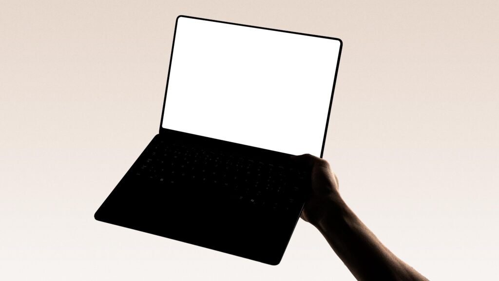 Eine Hand hält einen modernen Laptop vor neutralem Hintergrund – Symbol für flexibles Arbeiten mit Technologie.