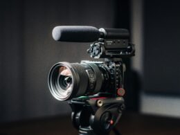 Nahaufnahme einer modernen Kamera mit montiertem Objektiv auf hellem Hintergrund, Fokus auf das Kameraobjektiv