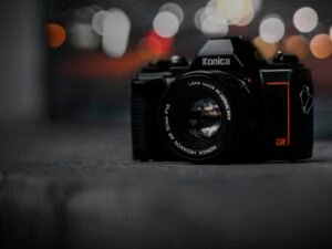 Kamera auf einem Tisch, im Hintergrund verschwommene Lichter in warmen Tönen, Fokus auf das Objektiv