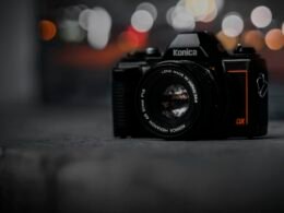 Kamera auf einem Tisch mit Hintergrund aus verschwommenen Lichtern, aufgenommen als modernes Fotomotiv in Innenräumen