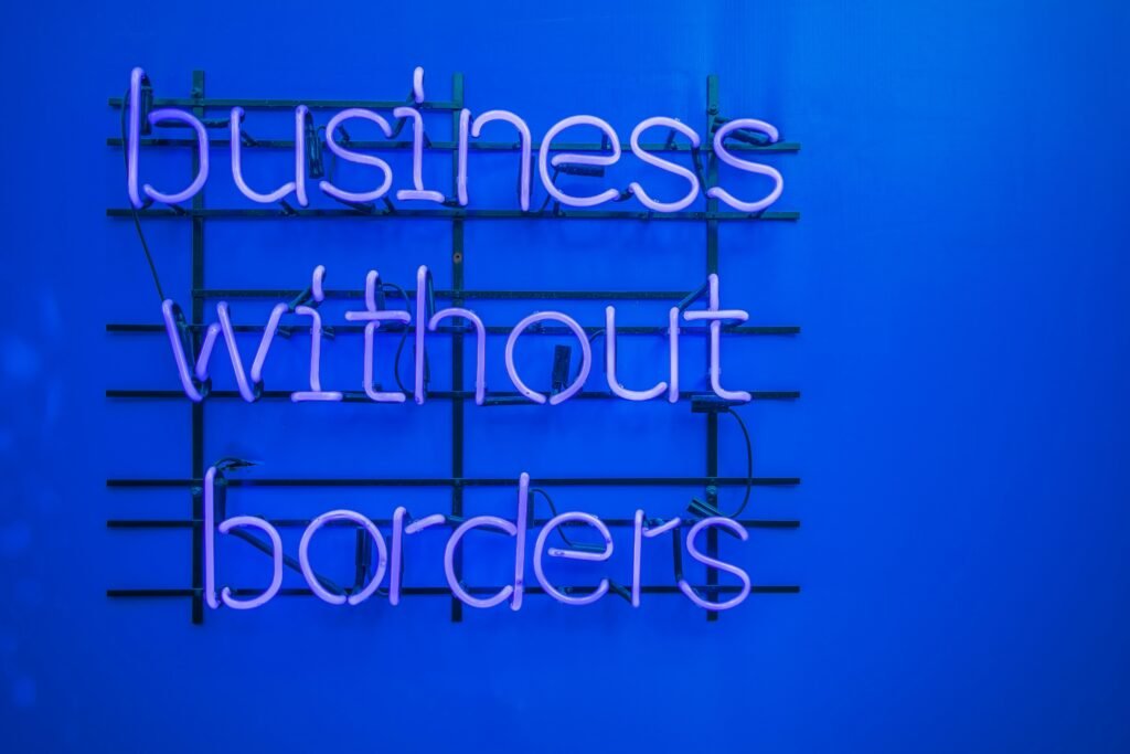 Neon-Schild mit der Aufschrift 'Business without borders' an einer dunklen Wand, Symbol für globale Unternehmensstrategien