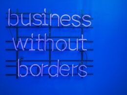 Neon-Schild mit der Aufschrift 'Business without borders' an einer dunklen Wand, Symbol für globale Unternehmensstrategien
