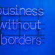 Neon-Schild mit der Aufschrift 'Business without borders' leuchtet in dunkler Umgebung und steht für globale Geschäftsmodelle.