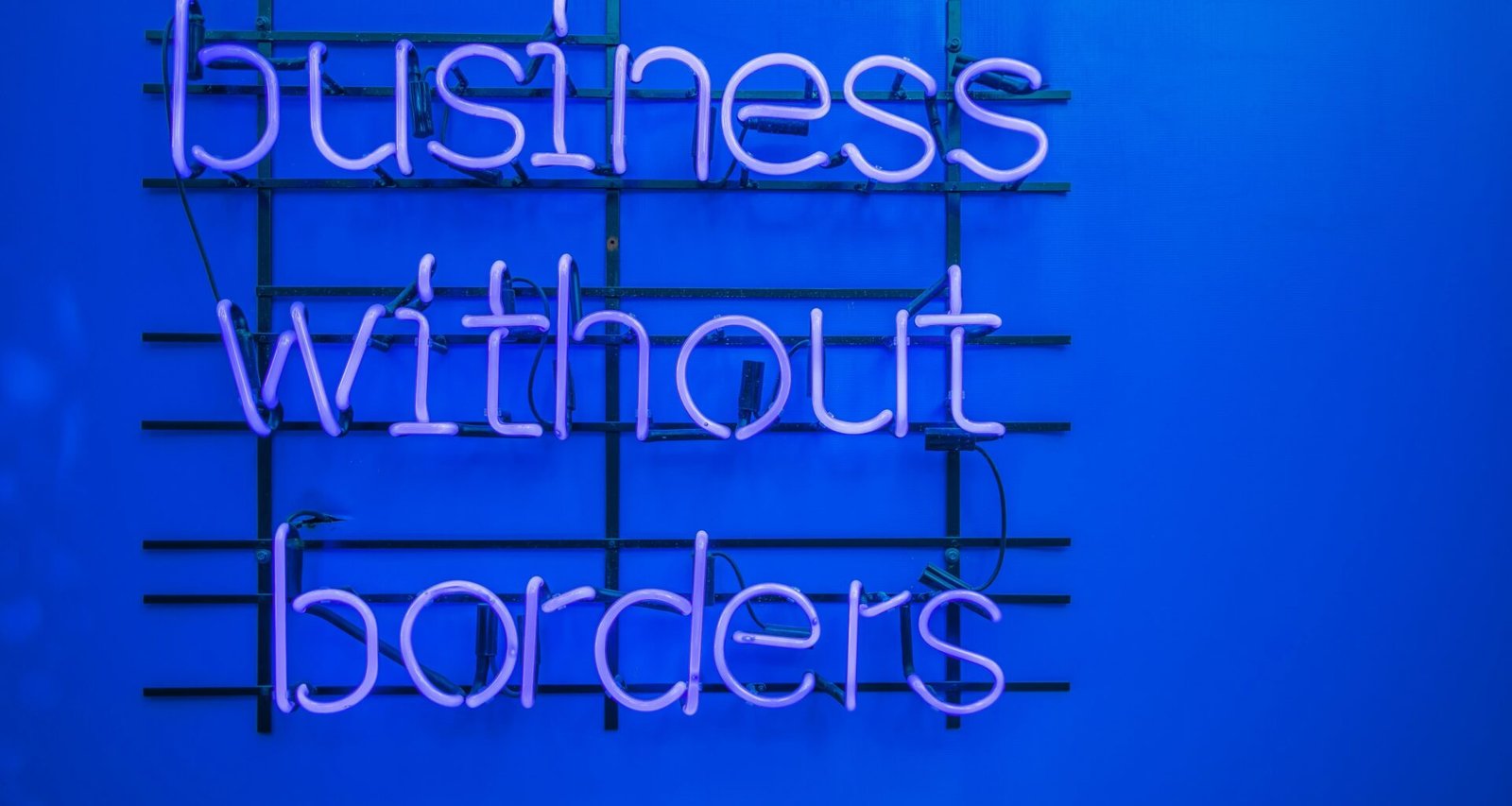 Neon-Schild mit der Aufschrift 'Business without borders' leuchtet in dunkler Umgebung und steht für globale Geschäftsmodelle.