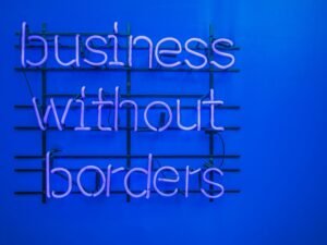 Neon-Schild mit der Aufschrift 'Business without borders' leuchtet in dunkler Umgebung und steht für globale Geschäftsmodelle.