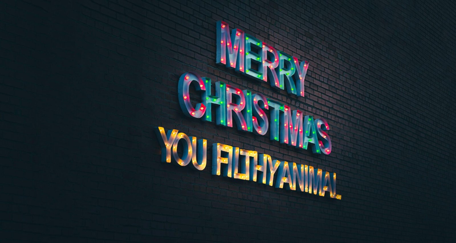 Leuchtendes Neon-Schild mit dem Schriftzug „Merry Christmas You Filthy Animal“ vor dunklem Hintergrund