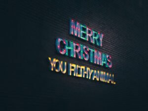 Leuchtendes Neon-Schild mit dem Schriftzug „Merry Christmas You Filthy Animal“ vor dunklem Hintergrund