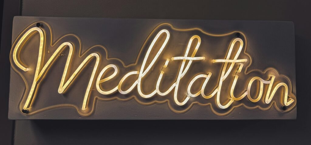 Leuchtendes Neon-Schild mit dem Wort Meditation in urbanem Stil auf dunklem Hintergrund
