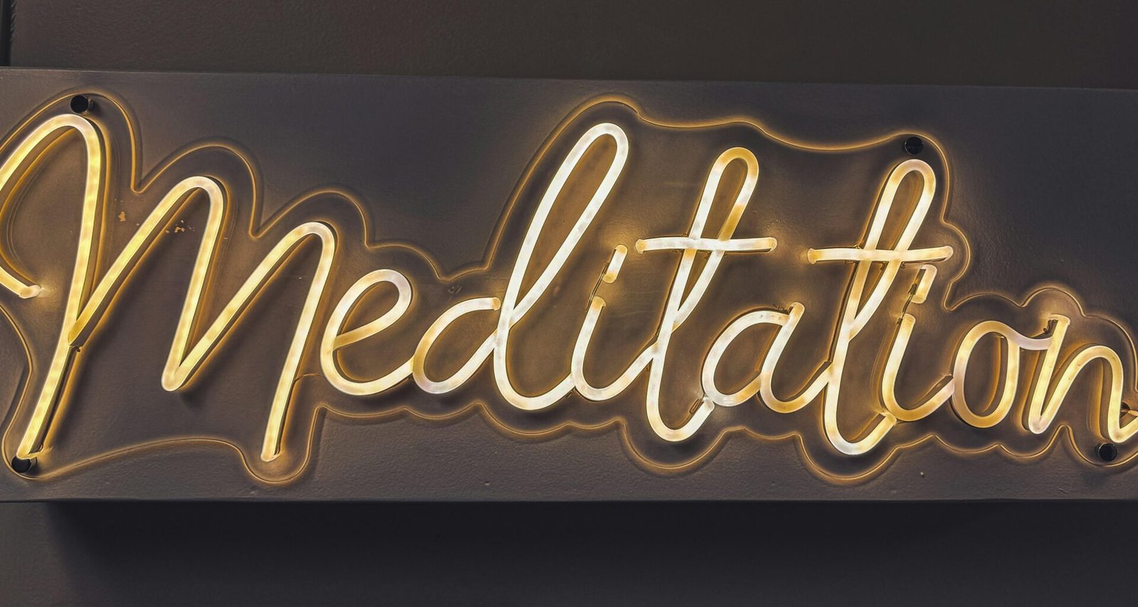 Leuchtendes Neon-Schild mit dem Wort Meditation in urbanem Stil auf dunklem Hintergrund
