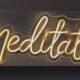 Leuchtendes Neon-Schild mit dem Wort Meditation in urbanem Stil auf dunklem Hintergrund