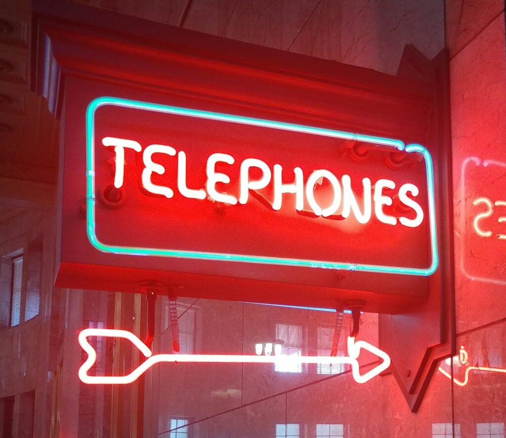 Ein leuchtendes Neon-Schild mit dem Schriftzug „Telephones“, das an der Wand angebracht ist