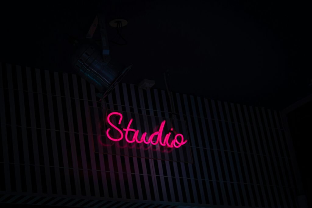 Neon-Schild mit der Aufschrift Studio an der Seite eines Gebäudes bei Nacht, modernes urbanes Stadtbild