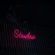 Neon-Schild mit der Aufschrift Studio an der Seite eines Gebäudes bei Nacht, modernes urbanes Stadtbild