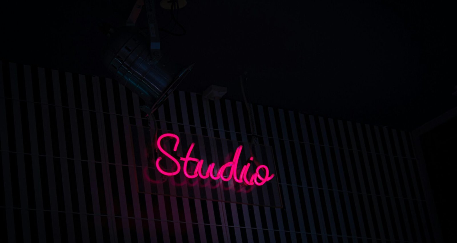 Neon-Schild mit der Aufschrift Studio an der Seite eines Gebäudes bei Nacht, modernes urbanes Stadtbild