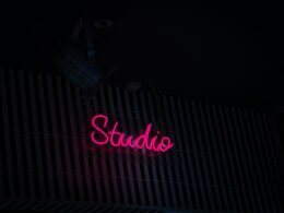 Neon-Schild mit der Aufschrift Studio an der Seite eines Gebäudes bei Nacht, modernes urbanes Stadtbild