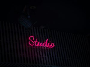 Neon-Schild mit der Aufschrift Studio an der Seite eines Gebäudes bei Nacht, modernes urbanes Stadtbild