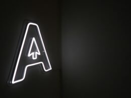 Leuchtender Neon-Schriftzug mit integriertem Pfeil auf dunklem Hintergrund, modernes Element für Online- und Technologiethemen