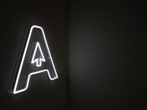 Leuchtender Neon-Schriftzug mit integriertem Pfeil auf dunklem Hintergrund, modernes Element für Online- und Technologiethemen