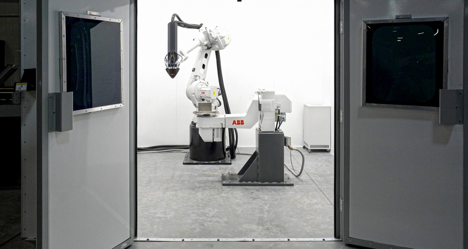 Eine Maschine steht zentral in einem technisch ausgestatteten Raum, verschiedene Leitungen und Geräte sind sichtbar.