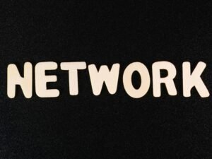 Nahaufnahme des Wortes 'Network' auf einer schwarzen Oberfläche, geeignet für Beiträge zu Technologie und digitalen Netzwerken