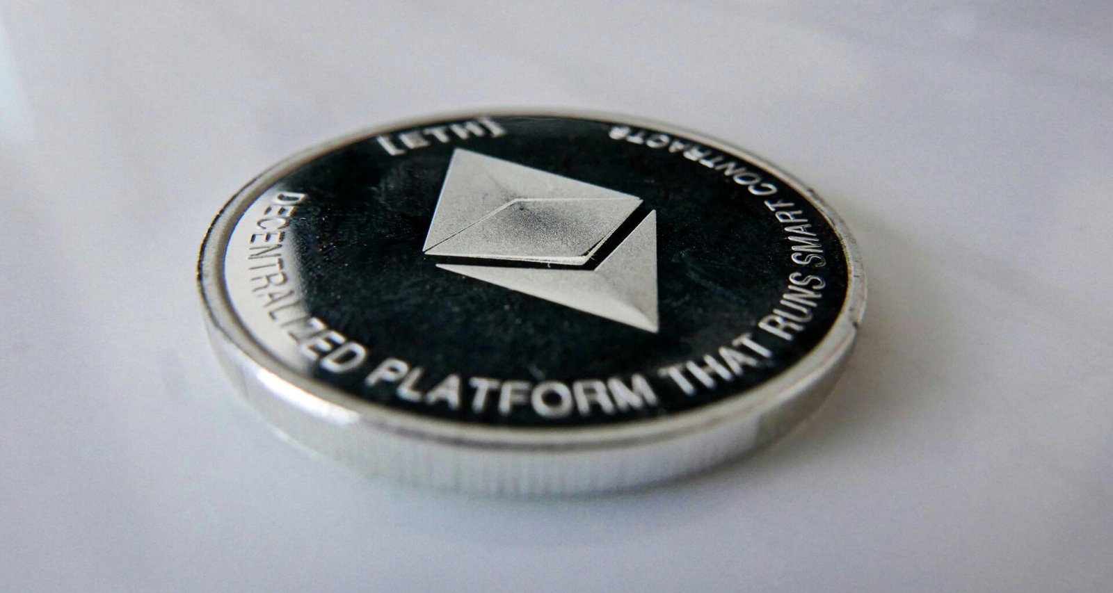 Nahaufnahme einer einzelnen Münze auf einem glatten Tisch, deutliche Details und Fokus auf die Kante der Münze