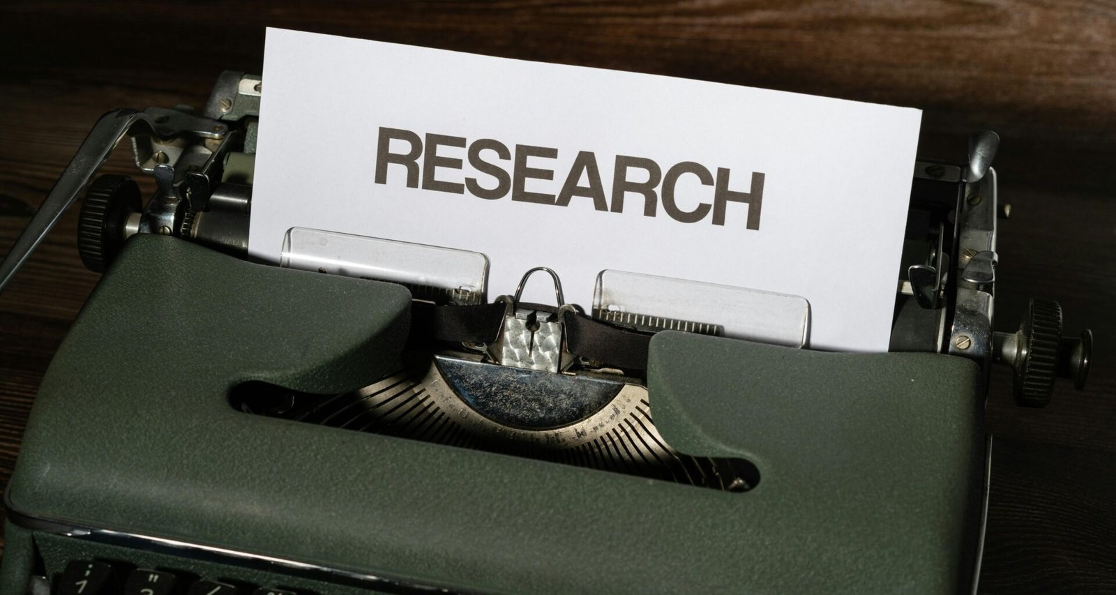 Nahaufnahme einer klassischen Schreibmaschine mit eingespanntem Papier auf einem Schreibtisch, Fokus auf die Tasten