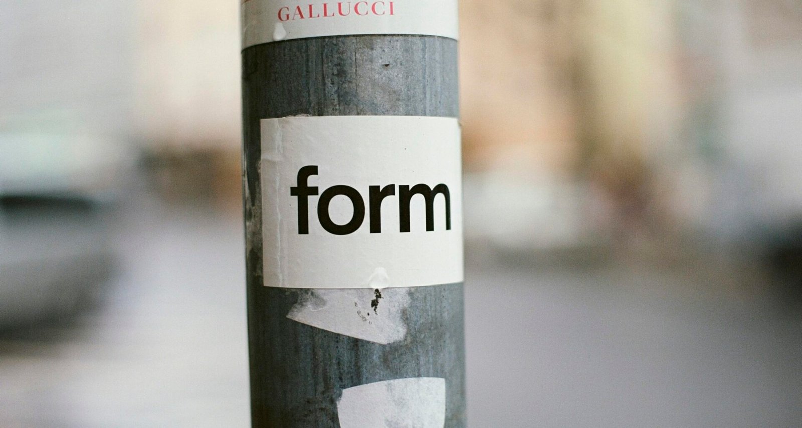 Ein Straßenpfosten mit einem Sticker aus nächster Nähe fotografiert, Fokus auf Sticker und Materialstruktur.