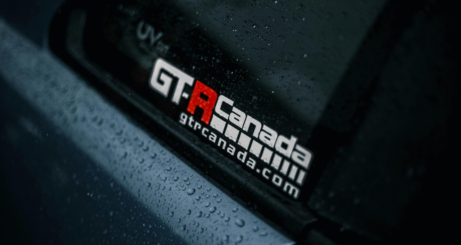 Nahaufnahme eines Autos mit zahlreichen Regentropfen auf der Karosserie, fotografiert bei feuchtem Wetter