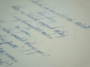 Detailaufnahme eines handgeschriebenen Briefes auf weißem Papier, Schriftzüge klar erkennbar, Nahaufnahme.