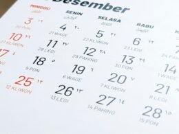 Nahaufnahme eines aufgeschlagenen Kalenders auf einem Tisch mit sichtbaren Terminen und Notizen.