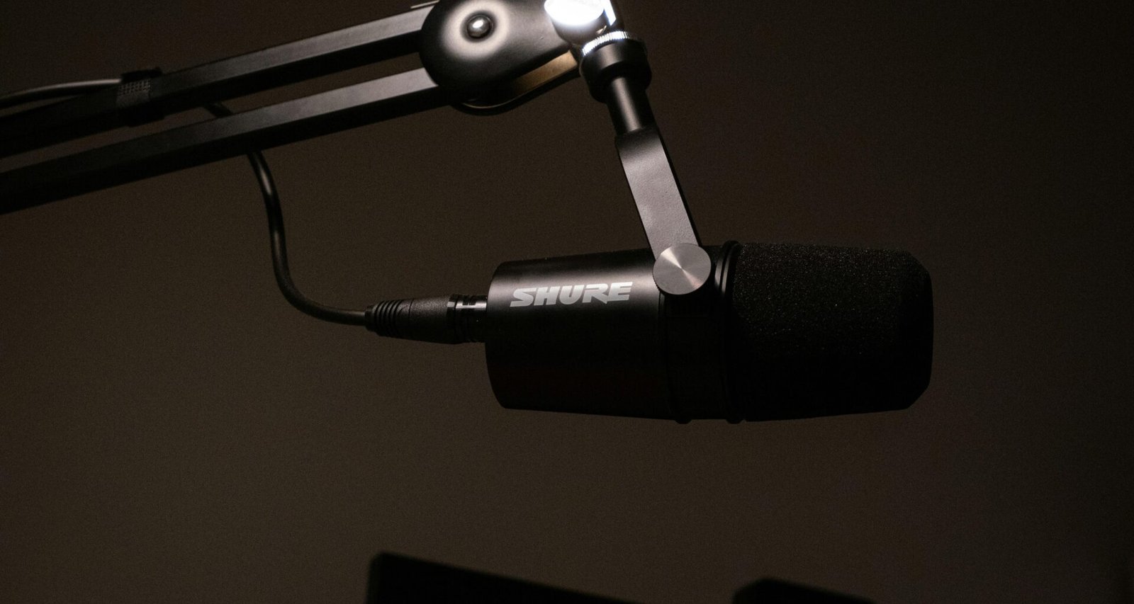 Detailaufnahme eines Mikrofons mit schwarzem Hintergrund, geeignet für Studioaufnahmen oder Podcasts