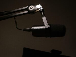 Detailaufnahme eines Mikrofons mit schwarzem Hintergrund, geeignet für Studioaufnahmen oder Podcasts
