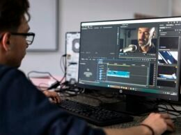 Person arbeitet an einem Computer und bearbeitet Videodateien mithilfe professioneller Software im Homeoffice.