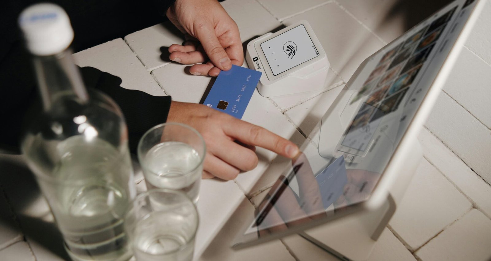 Eine Person begleicht ihre Bestellung kontaktlos auf einem Tablet an einer Verkaufstheke, digitale Zahlung im Geschäftsumfeld