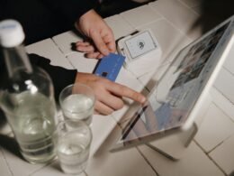 Eine Person begleicht ihre Bestellung kontaktlos auf einem Tablet an einer Verkaufstheke, digitale Zahlung im Geschäftsumfeld